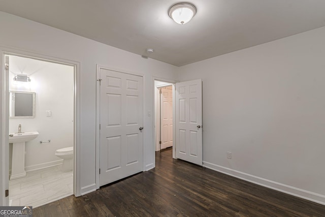 unfurnished bedroom with connected bathroom, sink, and dark wood-type flooring