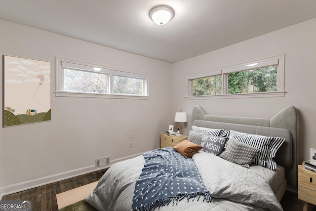 bedroom featuring multiple windows and dark wood-type flooring