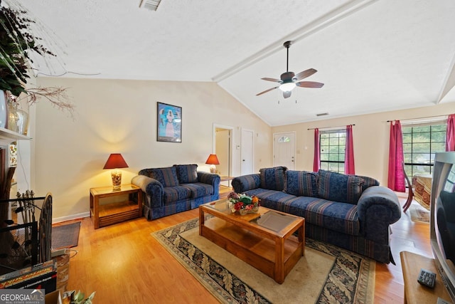 living room featuring ceiling fan, light hardwood / wood-style flooring, lofted ceiling with beams, and a textured ceiling