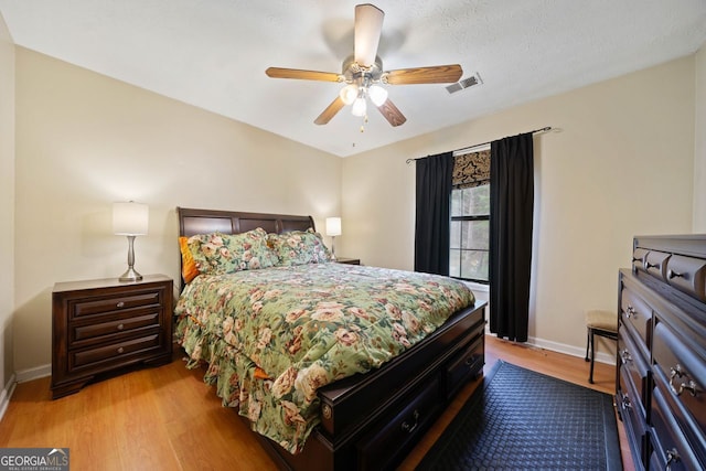 bedroom featuring ceiling fan, light hardwood / wood-style floors, and a textured ceiling