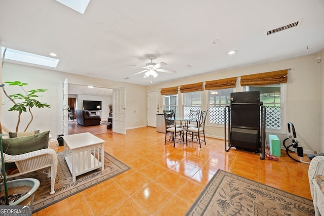 living room featuring light tile patterned floors, a skylight, and ceiling fan