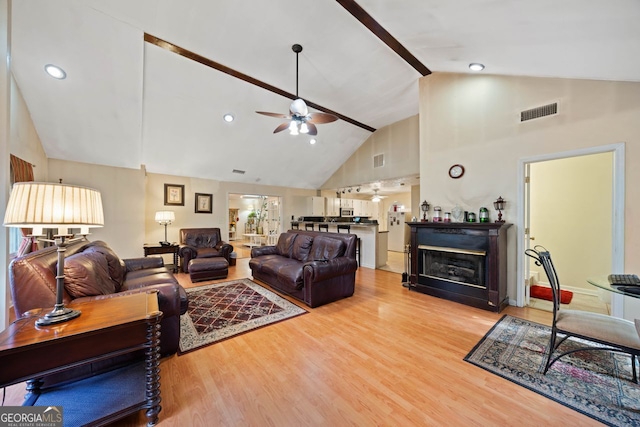 living room featuring ceiling fan, high vaulted ceiling, and light hardwood / wood-style floors