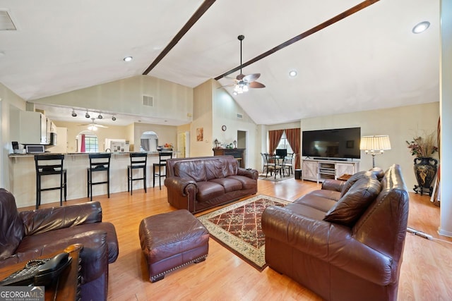 living room with ceiling fan, high vaulted ceiling, and light wood-type flooring