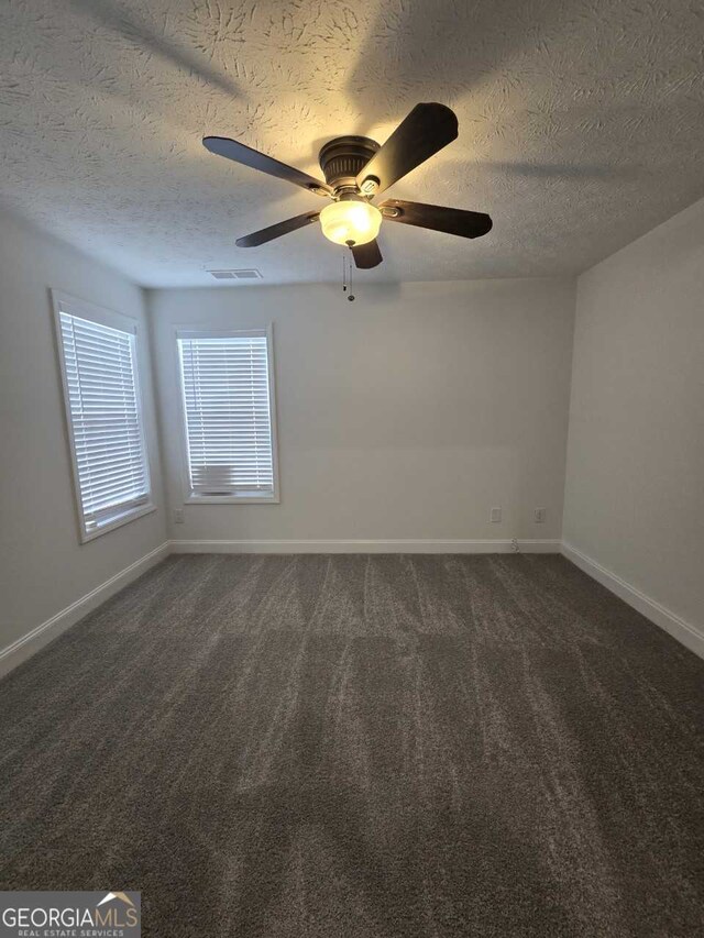 unfurnished room with ceiling fan, a textured ceiling, and dark colored carpet