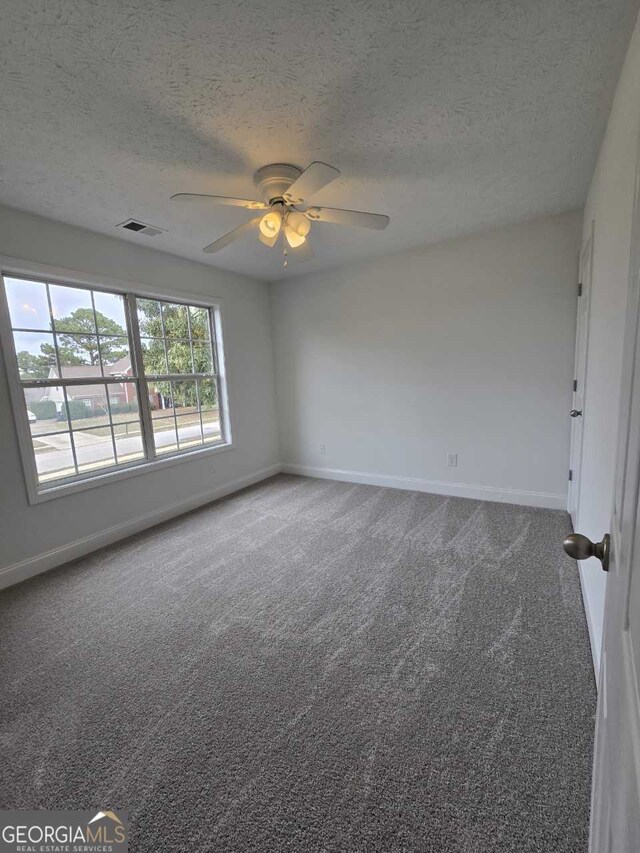 unfurnished room with ceiling fan, a textured ceiling, and carpet flooring