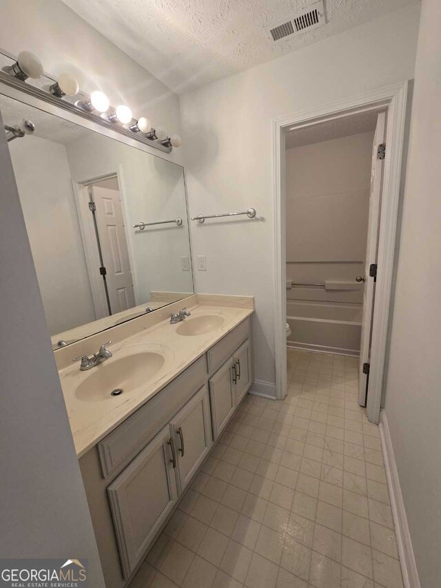 bathroom featuring a tub, toilet, tile patterned flooring, a textured ceiling, and vanity