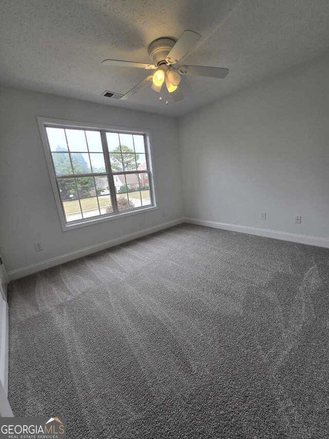 carpeted empty room featuring ceiling fan and a textured ceiling