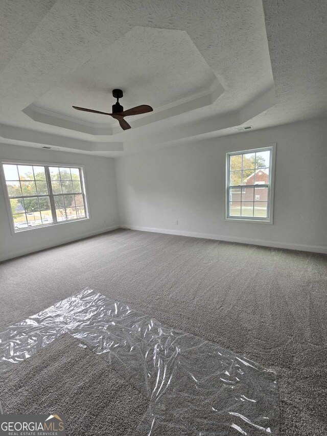 carpeted empty room featuring ceiling fan and a tray ceiling