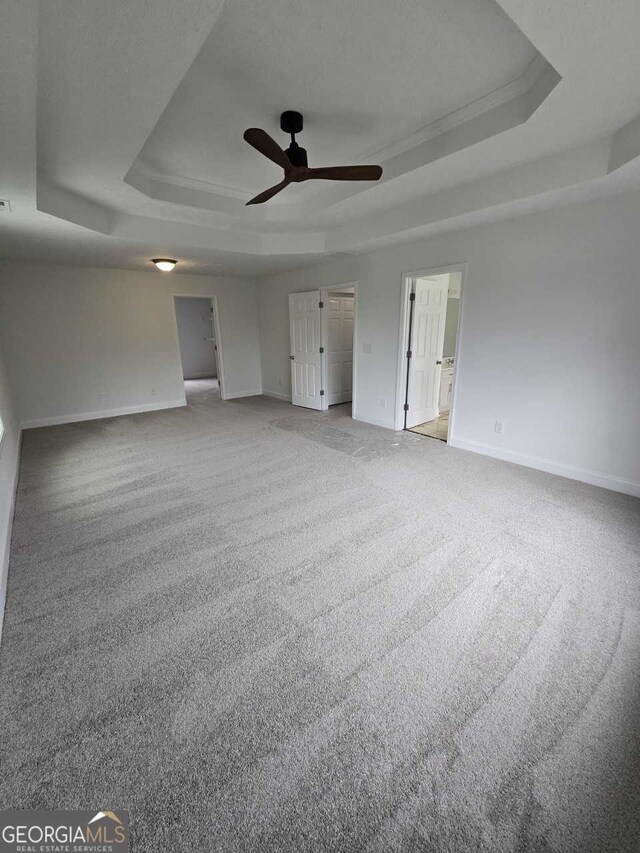 unfurnished room featuring carpet floors, ceiling fan, and a tray ceiling