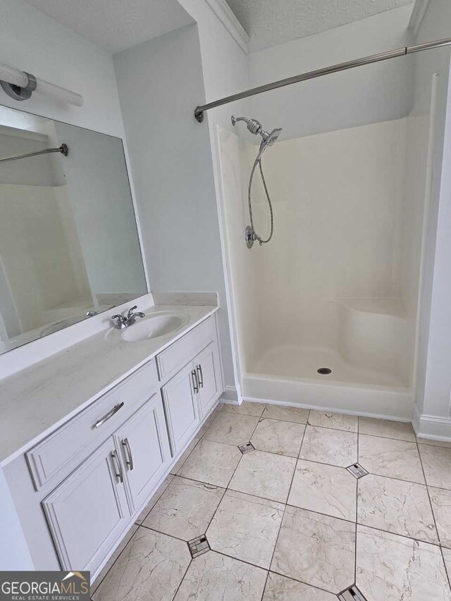 bathroom with a shower, a textured ceiling, and vanity