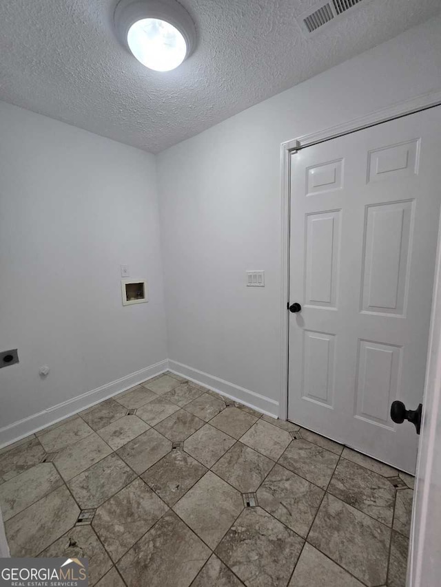 clothes washing area featuring hookup for a washing machine, electric dryer hookup, a textured ceiling, and tile patterned floors