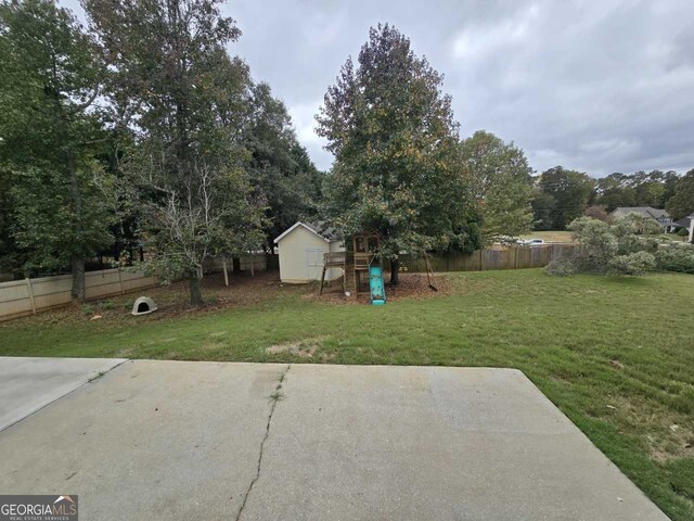 view of yard featuring a patio, a playground, and a storage unit