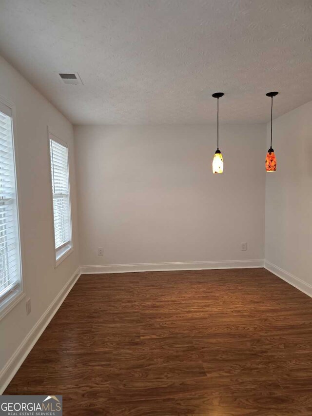 spare room with a textured ceiling and dark hardwood / wood-style flooring