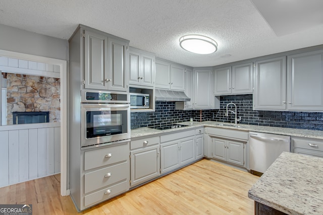 kitchen with stainless steel appliances, sink, tasteful backsplash, light hardwood / wood-style flooring, and gray cabinetry