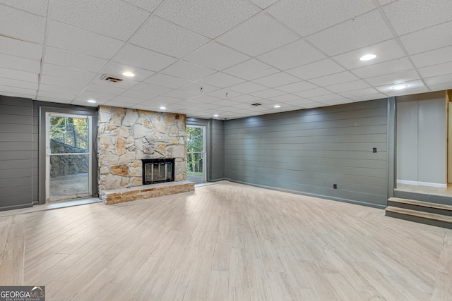 unfurnished living room featuring a drop ceiling, a fireplace, and light hardwood / wood-style flooring