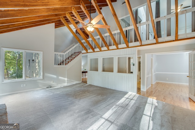 unfurnished living room with light hardwood / wood-style floors, ceiling fan, and high vaulted ceiling