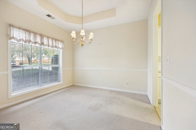 unfurnished room with carpet flooring, a raised ceiling, and a chandelier