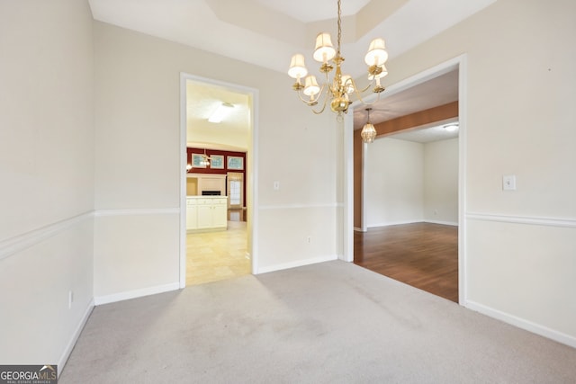 carpeted empty room with beam ceiling and a chandelier