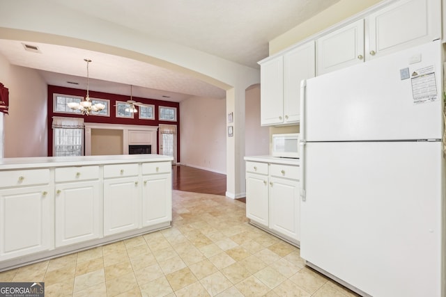 kitchen with ceiling fan with notable chandelier, white appliances, white cabinetry, and hanging light fixtures