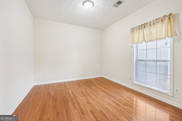 spare room featuring hardwood / wood-style flooring and a textured ceiling