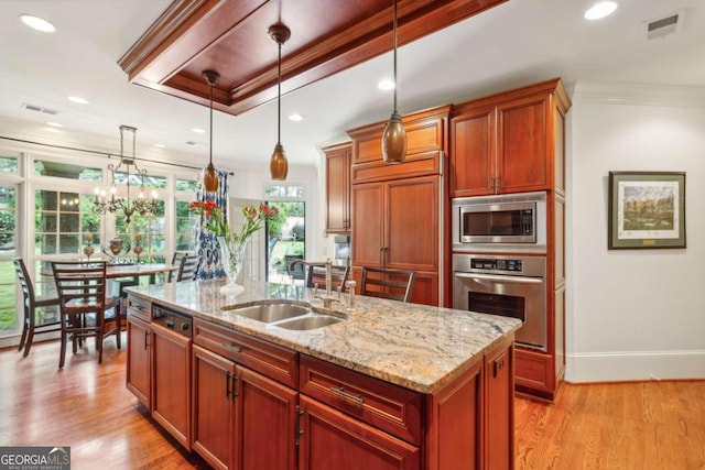 kitchen featuring pendant lighting, sink, built in appliances, and a kitchen island with sink