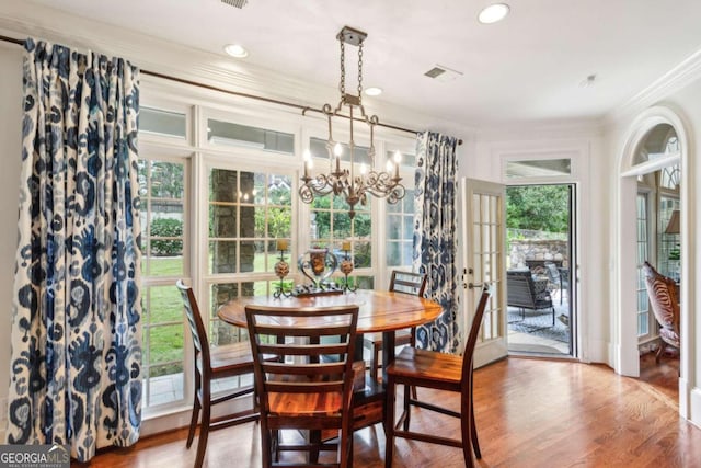 dining space featuring ornamental molding, hardwood / wood-style floors, plenty of natural light, and a chandelier