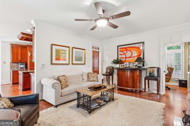 living room featuring ceiling fan, light wood-type flooring, and ornamental molding