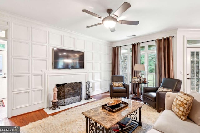 living room with ornamental molding, ceiling fan, and light hardwood / wood-style floors