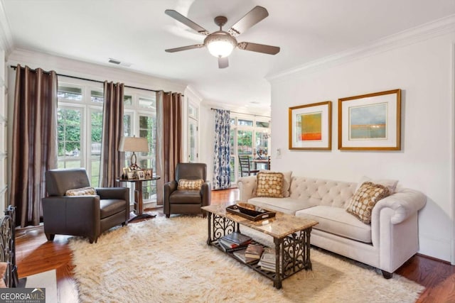 living room with hardwood / wood-style flooring, ceiling fan, and ornamental molding