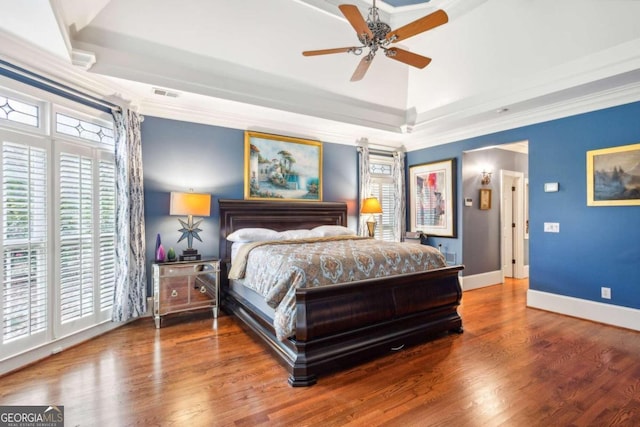 bedroom featuring a tray ceiling, hardwood / wood-style flooring, ceiling fan, and crown molding