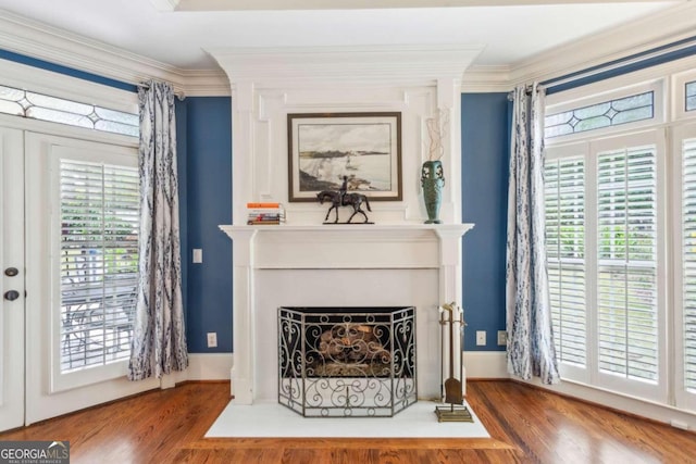 living room with ornamental molding, a large fireplace, and wood-type flooring