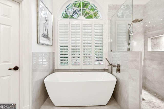 bathroom featuring tile walls and shower with separate bathtub