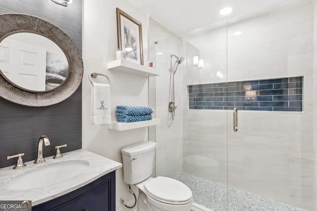 bathroom featuring toilet, vanity, and a shower with door