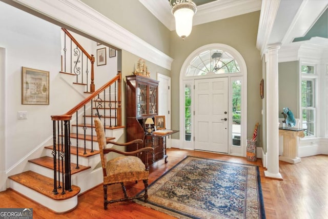 foyer featuring ornamental molding, wood-type flooring, and ornate columns