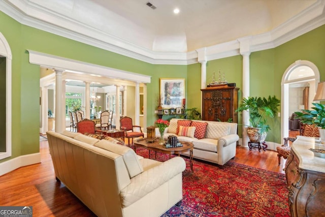 living room with hardwood / wood-style floors, an inviting chandelier, crown molding, and decorative columns