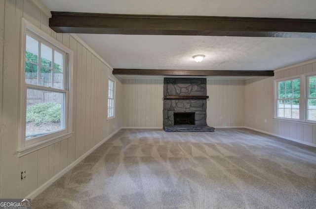 unfurnished living room featuring a fireplace, beamed ceiling, plenty of natural light, and carpet floors