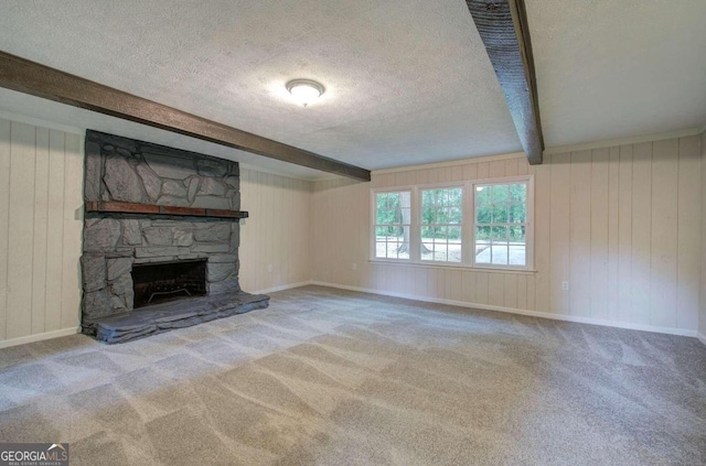 unfurnished living room with light colored carpet, a textured ceiling, wooden walls, beamed ceiling, and a fireplace