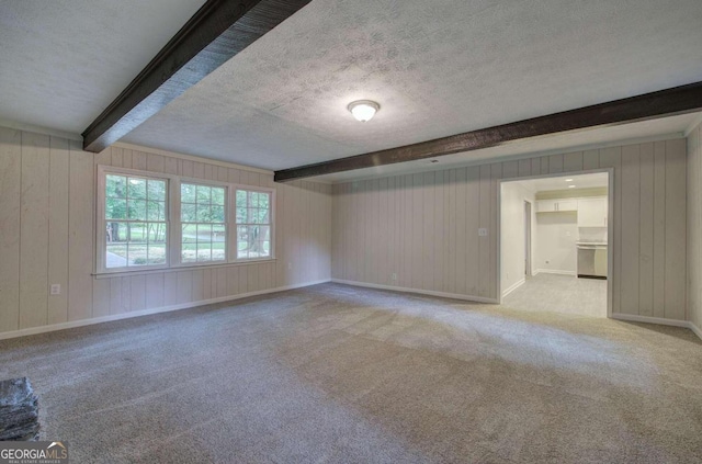 spare room featuring beamed ceiling, a textured ceiling, and light carpet