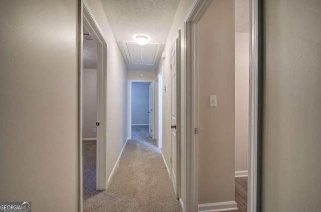 corridor with a textured ceiling and light carpet