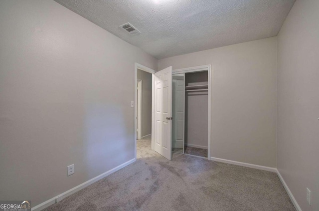 unfurnished bedroom featuring a textured ceiling, light carpet, and a closet