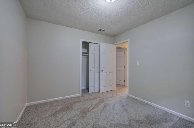 unfurnished bedroom with a textured ceiling, light carpet, and a closet