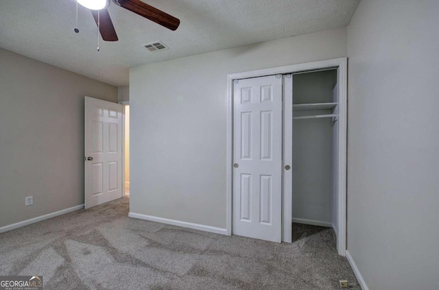 unfurnished bedroom with a closet, a textured ceiling, light carpet, and ceiling fan