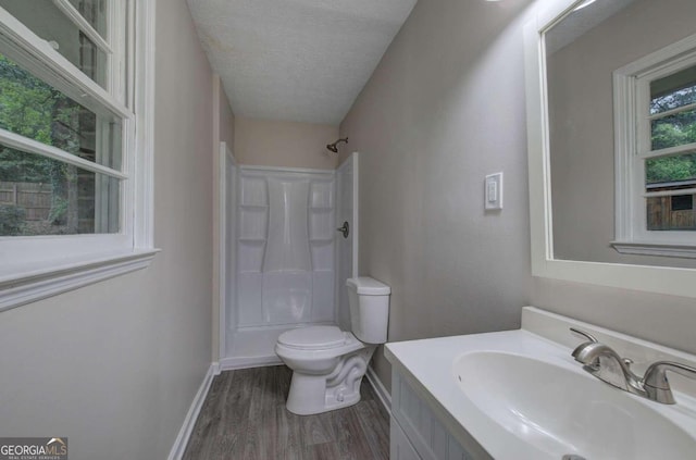 bathroom featuring walk in shower, vanity, a textured ceiling, hardwood / wood-style flooring, and toilet