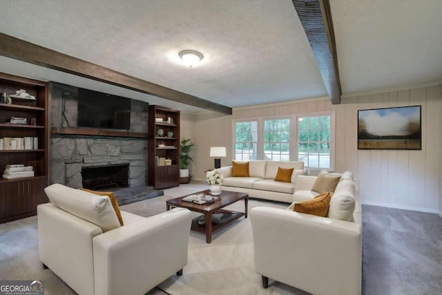 living room with a stone fireplace, wood walls, light carpet, a textured ceiling, and beam ceiling