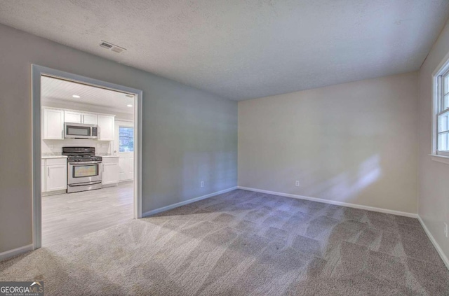 carpeted empty room with a textured ceiling