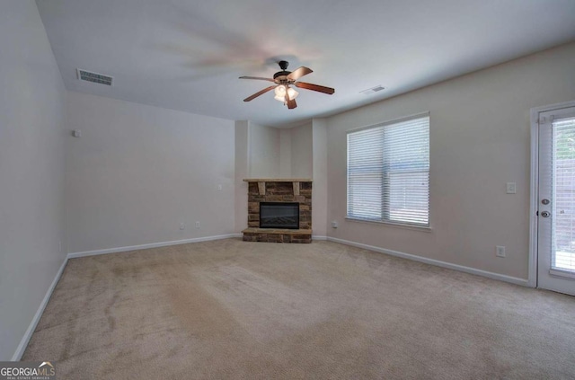 unfurnished living room featuring a fireplace, ceiling fan, and light carpet