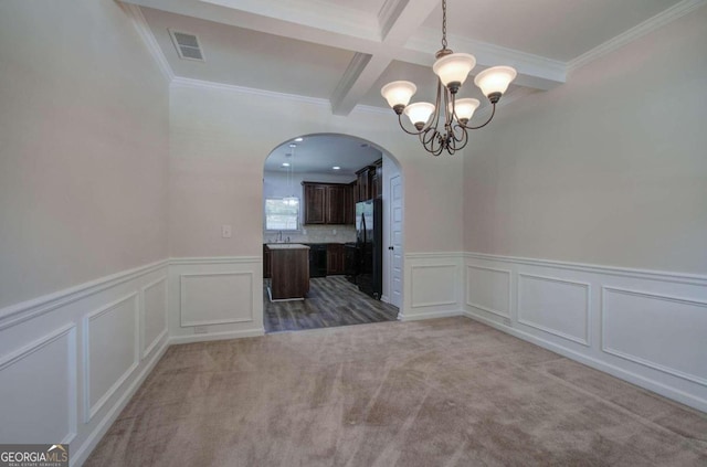 empty room featuring ornamental molding, carpet floors, sink, an inviting chandelier, and beamed ceiling