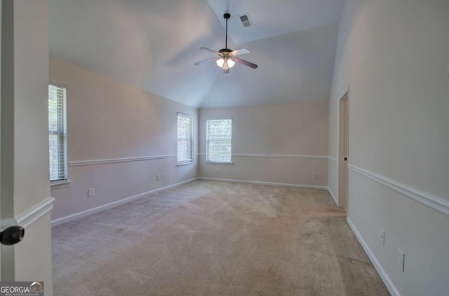 spare room with ceiling fan, light carpet, and vaulted ceiling