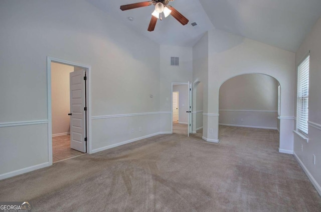 carpeted spare room with ceiling fan and high vaulted ceiling