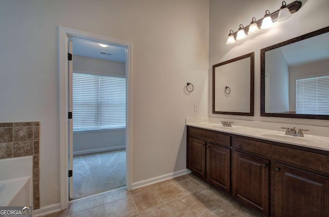 bathroom with a bathtub, vanity, and tile patterned flooring